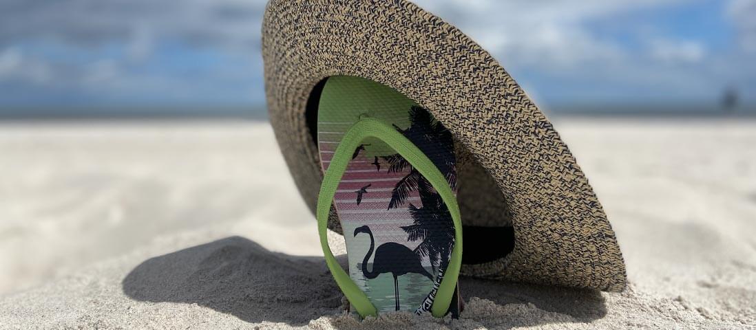 Der Schuh unter dem Sonnenhut am Strand